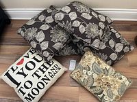 Six assorted throw pillows arranged on the floor showing different designs.