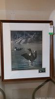 Framed and matted wildlife print featuring loons in a water scene.