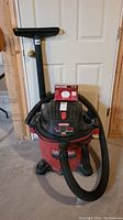 Front view showing Craftsman shop vac with attached hose, floor nozzle attachment mounted on hose, and cloth filter box on top.
