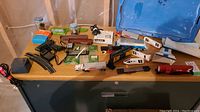 Tabletop view of various vintage AFX Turbo trains, cars, trucks, controllers, and tracks arranged together