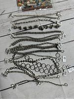 Photo showing 18 pewter bead chains and bracelets laid flat with tags attached, depicting a variety of designs and chain styles.