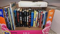 Side view of box showing a row of various books including The Art of Disney, Star Trek, Warhammer 40,000, and others