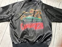 Front and back close-up of jacket showing airbrushed green Camaro Z28 car, red Chevrolet logo and 'Camaro Z28' text on shiny black satin fabric