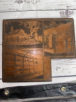 Top view of metal print plate featuring three engraved scenes with visible rust and wear.