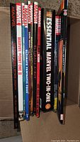 Box with 10 Marvel trade paperback comic books showing spines, includes titles like Essential Marvel Two-in-One, Ultimate X-Men, Marvel Point One II, etc.
