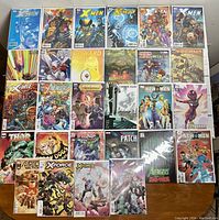 Top-down view of 28 modern comic books spread on a wooden surface. Covers include X-Men, Spiderman, Thor, Avengers, Star Wars, Howard the Duck, Iron Man, Wolverine, New Men, X-Force, and Flash titles. Comics appear in clear protective sleeves.