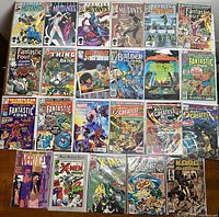 Top-down image showing all comic books laid out in rows on a wooden surface, displaying cover art and titles of New Mutants, Fantastic Four, Marvel Point One, X-Men and others.