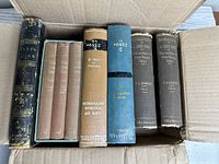 Top-down view of the boxed set and other books in a cardboard box showing some wear on covers and spines.