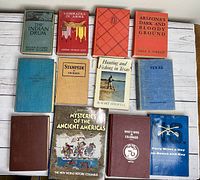 Box with 13 antique and vintage American history and related books arranged on white wooden surface.