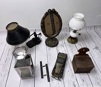Front view of the lot with all items showing black metal lamp, lantern, mirror, wooden box, toy car and lamp.