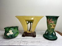 The three Roseville pottery vases arranged side by side, showing shapes and colors of each piece including yellow 1058 vase in center.
