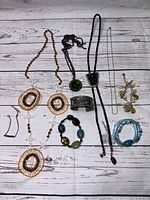 Top-down photo showing all southwestern style jewelry items arranged on wooden floor: necklaces, cuff bracelet, earrings, and bracelets in various colors and materials.