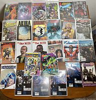 Photo showing the full lot of 29 comic books arranged on a wooden surface, featuring titles like The Boys, Akira, Herogasm, Wildcats, and others.