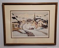 Frontal photo of the framed print showing the full artwork including village scene and mountains.