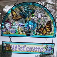 Full view of the semi-circular floral and butterfly suncatcher with attached rectangular welcome sign panel, showing the painted design and hanging chain.