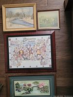 Group photo of seven framed artworks on floor, showing various sizes and subjects including winter landscape, historic print, and needlework.