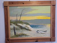 Front view of the large oil painting showing seaside dunes with beach grass and two small boats on the shore under a stormy sky, framed in wood.