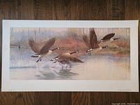 Full view of the print laid flat, showing the Canada Geese in flight over water with a natural landscape background.