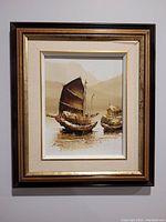 Framed oil painting showing two traditional Chinese junk boats on water with soft mountainous background.