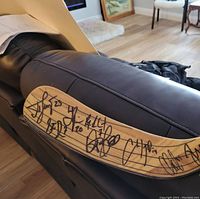 Close-up of hockey stick blade showing several autographs in black marker, including Steve Downie (#7)