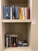 Two shelves of assorted fiction books showing spines and some cover text.