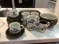Full lot showing cups, saucers, creamer jug, and serving bowl on a countertop.