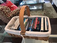 Photo of basket filled with DVDs showing case tops and fabric lining basket with wooden handle.
