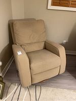 Side angle view showing the beige fabric, cushioned seat and armrest, and swivel base.