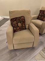 Front view of beige Lazboy reclining armchair with matching floral pillow on seat showing overall condition and wear.