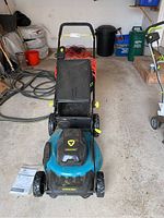 Front view of the Yardworks electric mower showing the included manual and power cord coiled behind.