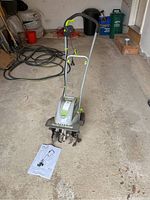 Full view of tiller with manual on garage floor