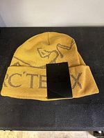 Front view of yellow Arc'teryx Bird Word toque with folded brim showing logo and branding.