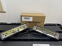 Pair of Lightfox LED lights displayed with their original packaging on a black surface.