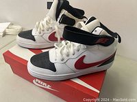 Side view of the Nike kids shoes showing the white, black, and red color pattern and Nike swoosh.