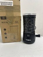 Photo showing Paris Rhone milk frother next to its original damaged box, unit is upright and plugged in for display.