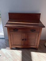 Full front view of the antique solid oak washstand highlighting the drawer and cabinet doors.