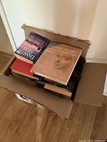 Box containing several used books including 'Drawing on the Right Side of the Brain' by Betty Edwards and a novel by Danielle Steel on top.
