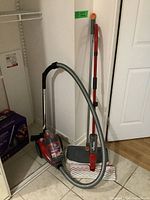 Photo of Dirt Devil Featherlite vacuum cleaner with flexible hose and two wide floor mops leaning against wall