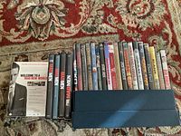 Photo showing a lineup of DVDs including Mad Men Season 1-4 and other movie titles placed on a red patterned carpet.