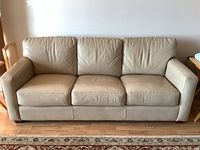 Front view of three-seater cream leather sofa showing overall condition and color.