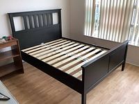 Front left three-quarter view of assembled black Hemnes bed frame showing headboard, slats, and footboard