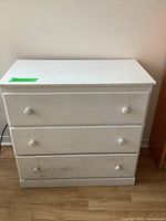 Front view of vintage painted wooden dresser showing three drawers and signs of wear