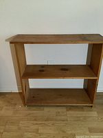 Front view of small vintage solid wood bookcase showing natural wear and wood grain.