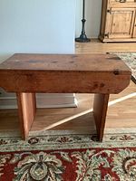 Side view of the wooden bench showing its solid blocky legs and top surface with natural wood knots and wear.