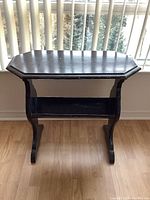 Front view of the vintage wooden bookstand showing the octagonal top, curved vertical supports, and lower shelf.