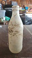 Front view of antique Coca-Cola glass bottle showing embossed logo and wear from age.