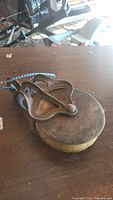 Antique pulley block showing wooden wheel and cast iron frame from side angle, with blue and white nylon rope attached.