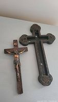 Two-piece metal crucifix displaying front and back pieces separated, placed side by side showing details and clip mechanism.