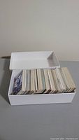 White box filled with many sports cards viewed from the top showing large stack.