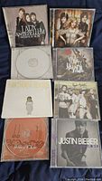 Photo showing eight CDs including Lady Antebellum, The Band Perry, Justin Bieber, Hawthorne Heights, and Miley Cyrus albums.